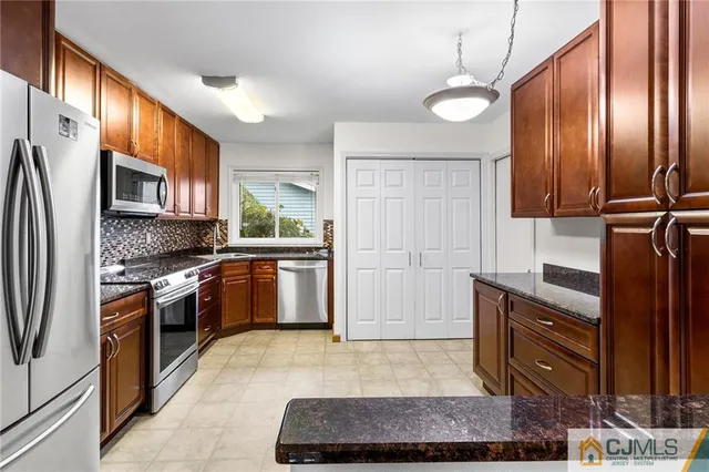 a kitchen with granite countertop stainless steel appliances a stove a sink cabinets and a refrigerator