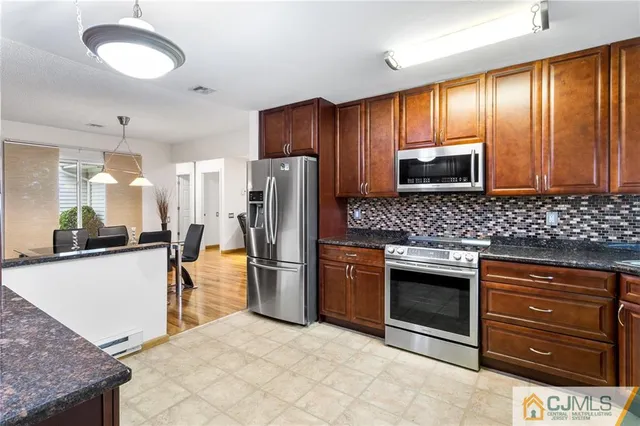 a kitchen with stainless steel appliances granite countertop a refrigerator a stove a sink and a microwave