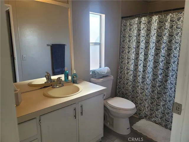a bathroom with a granite countertop sink toilet and mirror