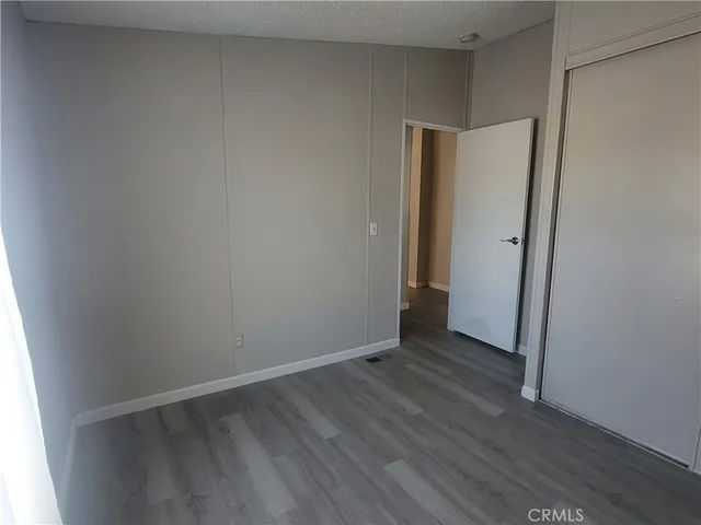 a view of an empty room with wooden floor and closet