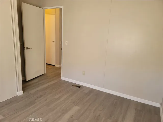 a view of an empty room with wooden floor and closet
