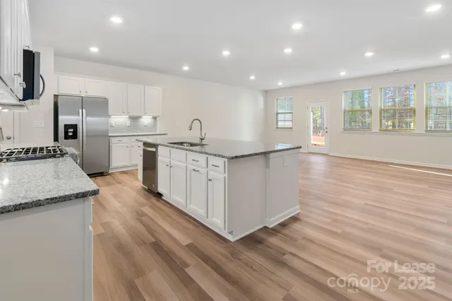 a kitchen with stainless steel appliances granite countertop a sink a stove and a refrigerator