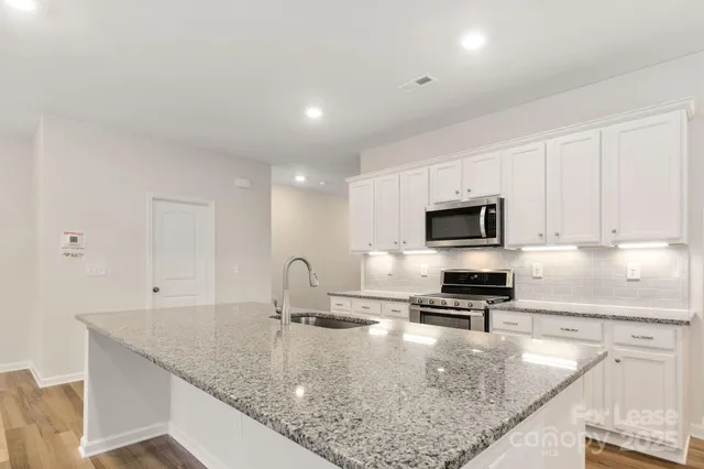 a kitchen with stainless steel appliances granite countertop a sink a stove and microwave