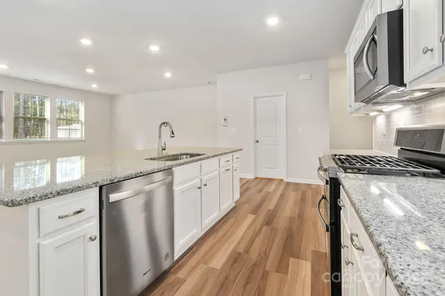 a kitchen with granite countertop a sink stove and cabinets