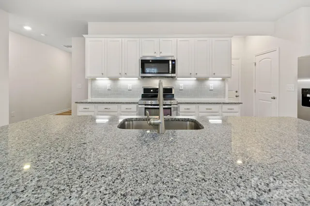 a kitchen with granite countertop a sink and a stove top oven