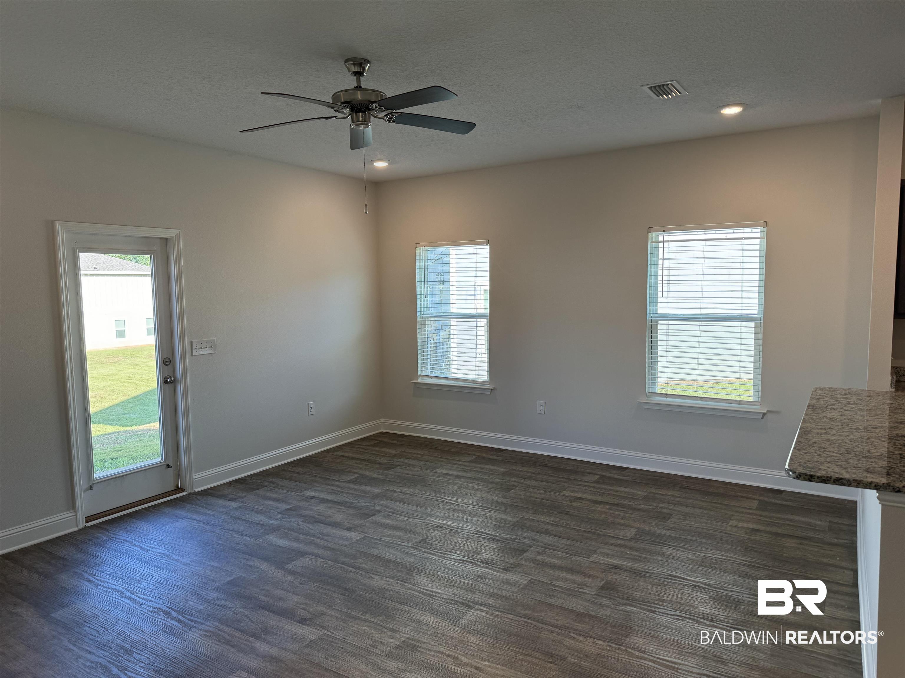 25806 Pollard Road, Unit 42 Daphne, AL 36526 - Photo 3 of 21 Unfurnished living room with ceiling fan, a healthy amount of sunlight, and dark hardwood / wood-style flooring