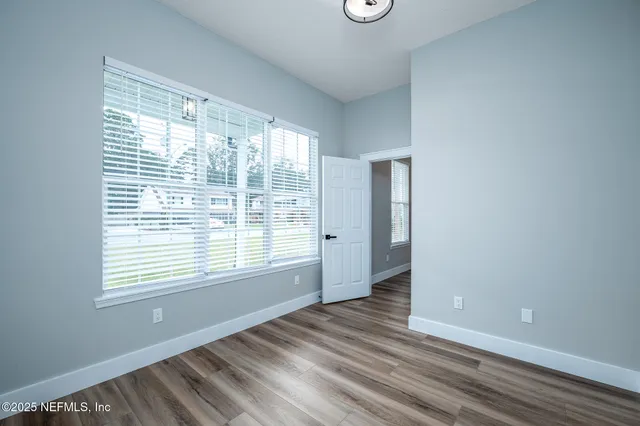 a view of an empty room with wooden floor fireplace and a window