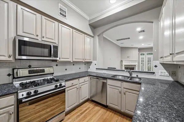 a kitchen with stainless steel appliances granite countertop a sink a stove a microwave and cabinets