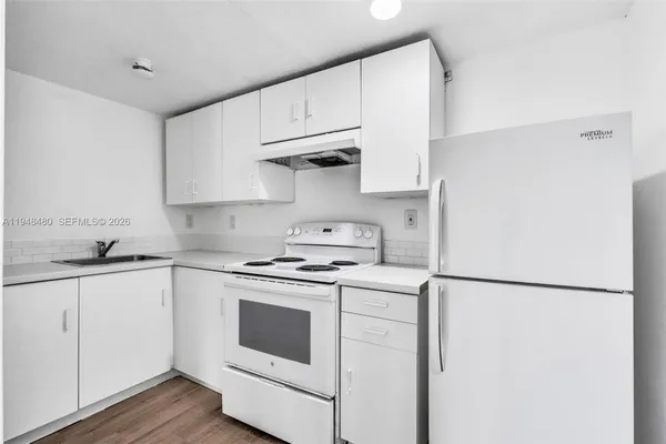 a kitchen with cabinets appliances and wooden floor