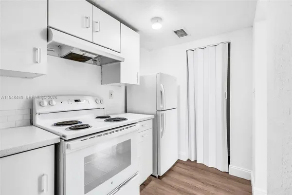 a kitchen with stainless steel appliances white cabinets and wooden floor