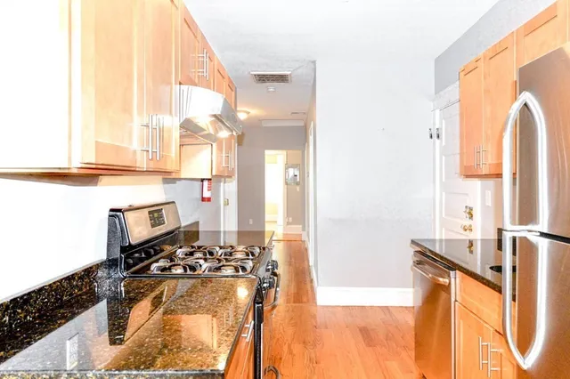 a kitchen with stainless steel appliances kitchen island granite countertop a stove a sink and a refrigerator