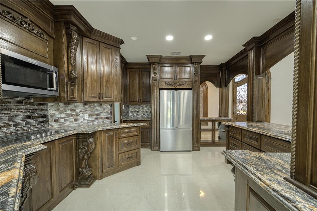 2916 Fletcher Street Weslaco, TX 78599 - Photo 11 of 45 a kitchen with stainless steel appliances granite countertop a refrigerator a sink and wooden cabinets