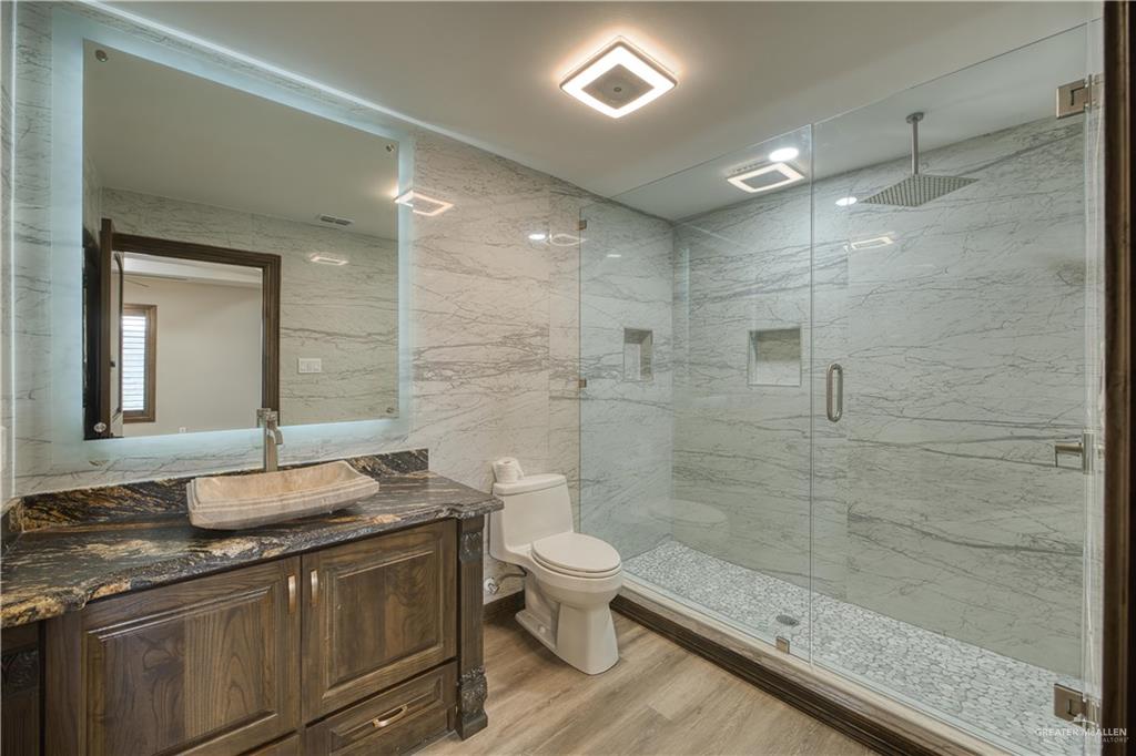 2916 Fletcher Street Weslaco, TX 78599 - Photo 38 of 45 a bathroom with a granite countertop sink a toilet a mirror and shower