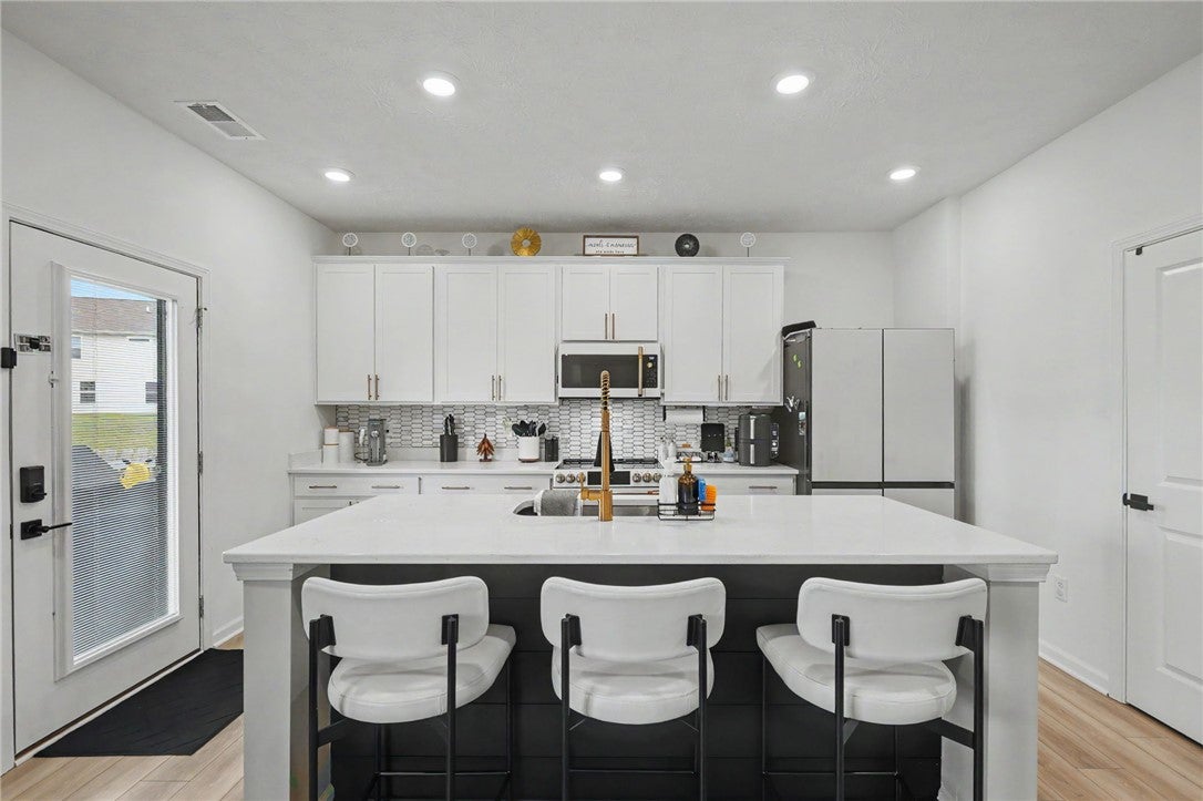 3011 Falls Road Clayton, OH 45315 - Photo 23 of 66 A contemporary kitchen showcasing crisp white cabinetry and a practical central island for dining.