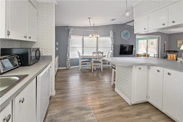 a kitchen with stainless steel appliances granite countertop a stove top oven a refrigerator a dining table and chairs with wooden floor