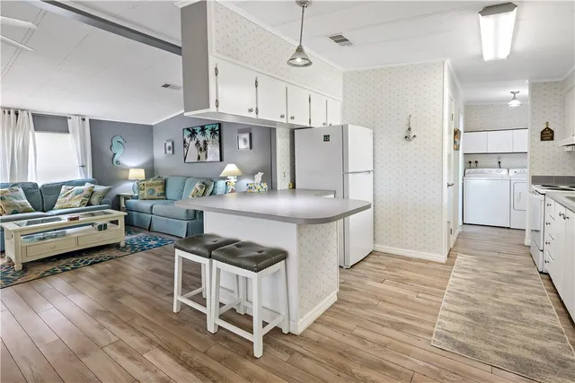 a kitchen with stainless steel appliances kitchen island granite countertop a stove a refrigerator and a dining table with wooden floor