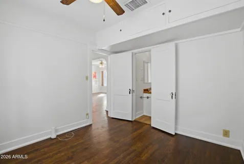 an empty room with wooden floor ceiling fan and windows