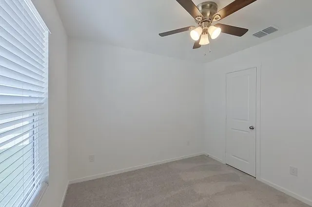 an empty room with a window and a fan