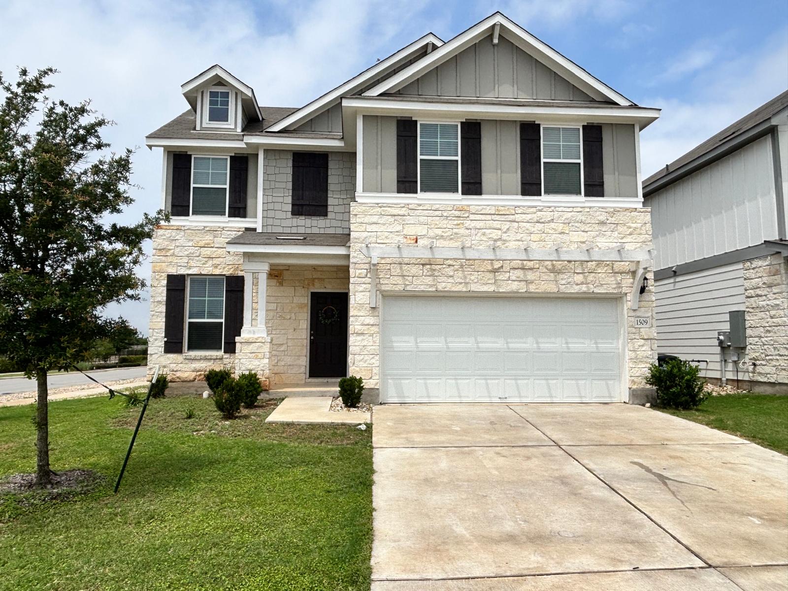 Craftsman-style home with stone siding, an attached garage, concrete driveway, and a front yard