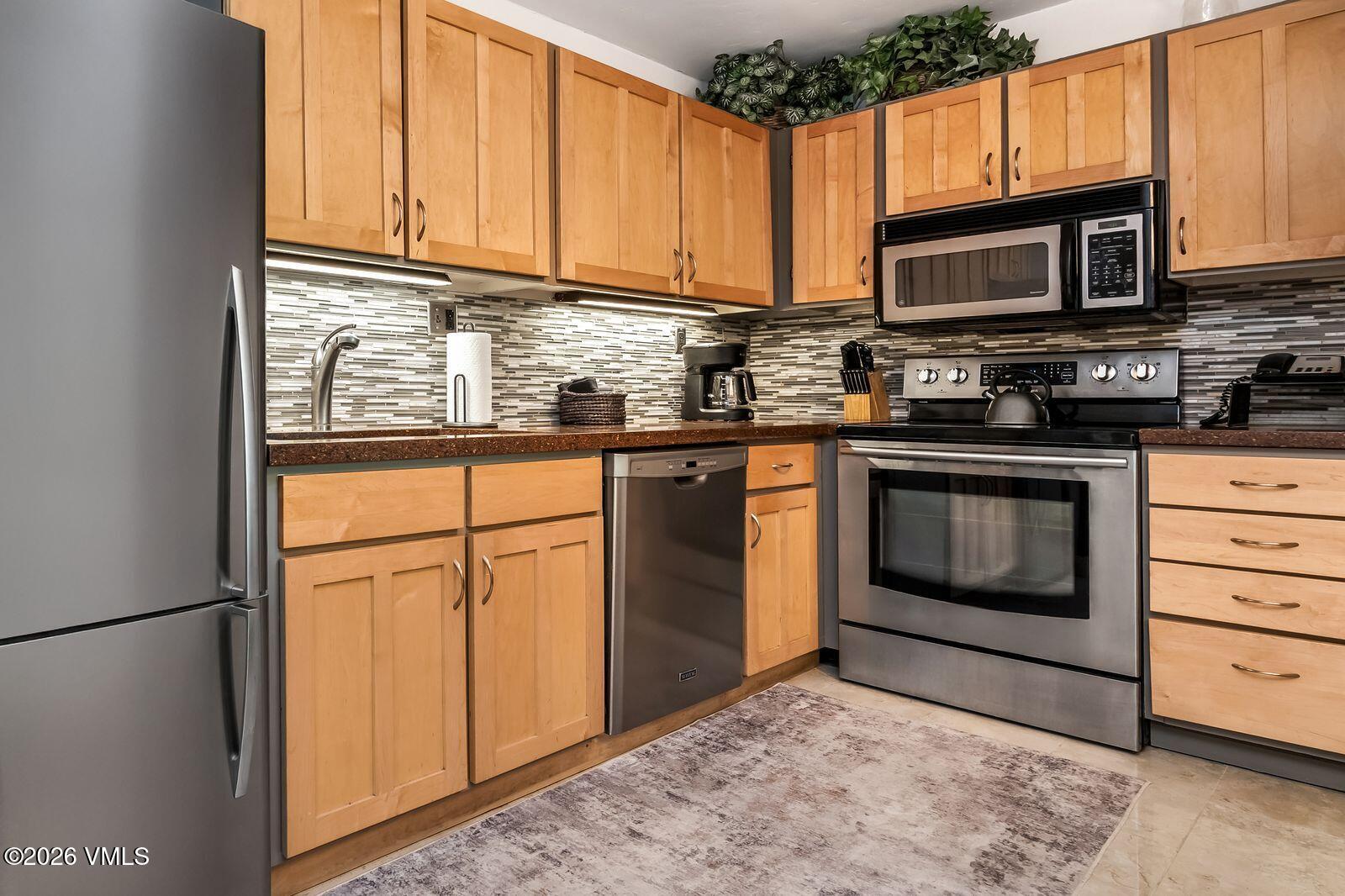 500 South Frontage Road East, Unit 308 Vail, CO 81657 - Photo 8 of 25 a kitchen with stainless steel appliances granite countertop a stove microwave and cabinets