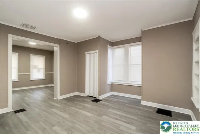 an empty room with wooden floor and windows