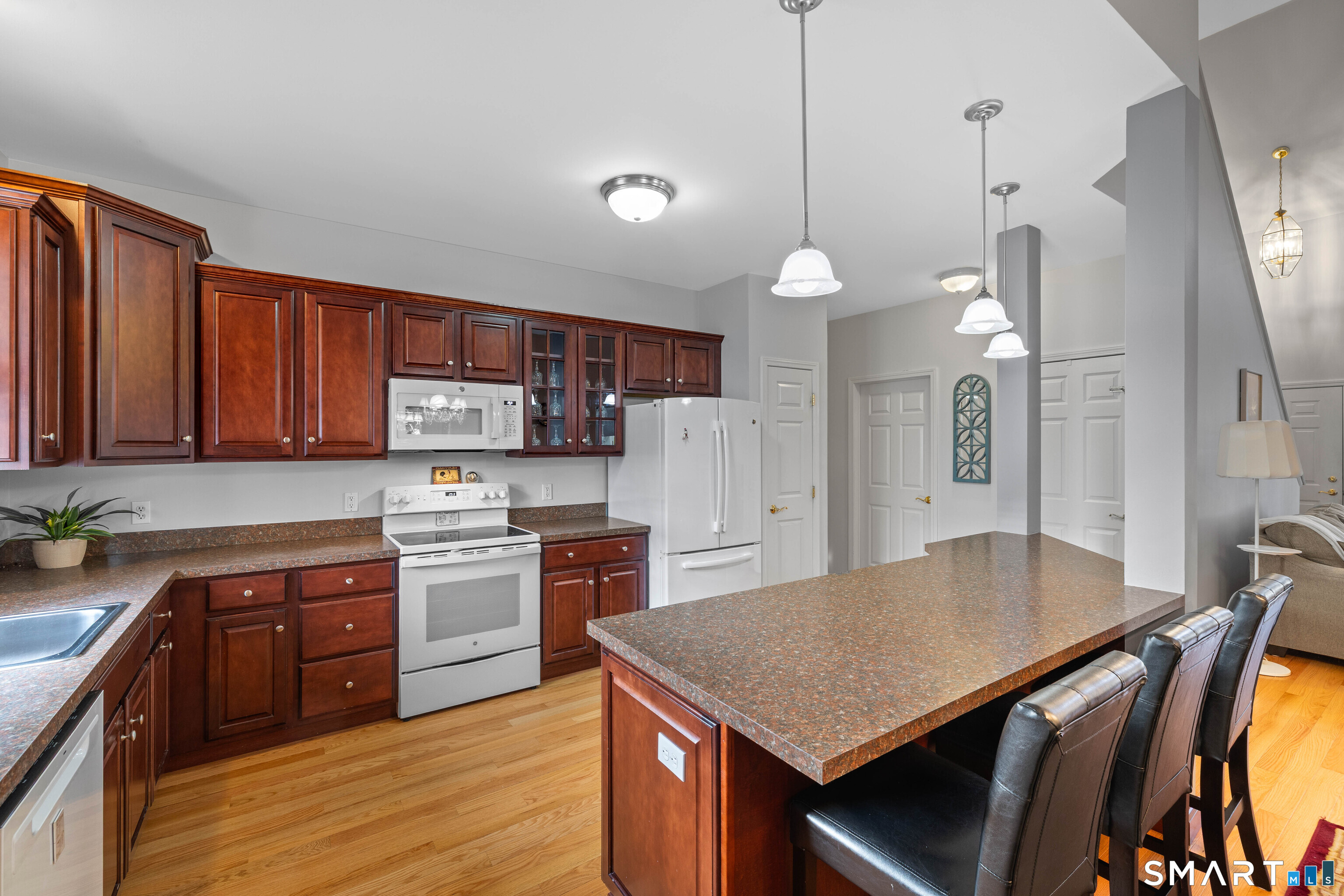 24 Phillips Farm Road, Unit 24 East Hartford, CT 06118 - Photo 14 of 34 a kitchen with stainless steel appliances granite countertop a stove a refrigerator a sink dishwasher and a dining table with wooden floor