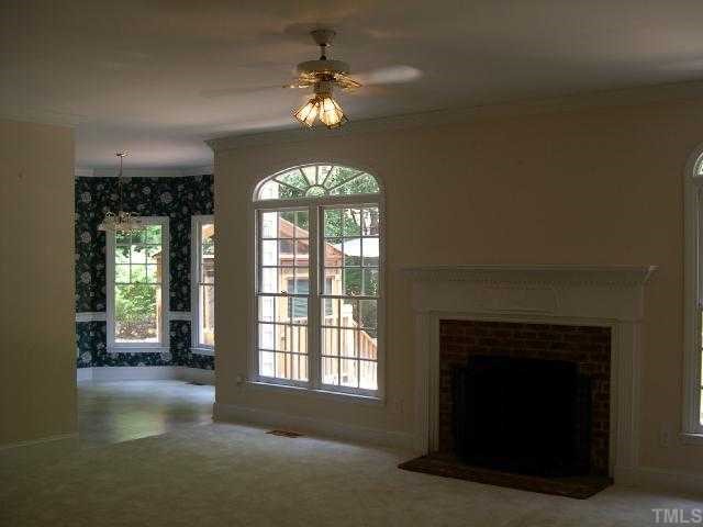 1704 Crown Glenn Place Raleigh, NC 27613 - Photo 4 of 4 an empty room with a fireplace and chandelier