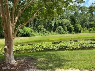 an empty room with wooden floor chandelier and windows