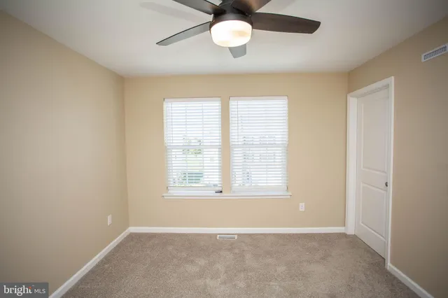 an empty room with a window and a fan
