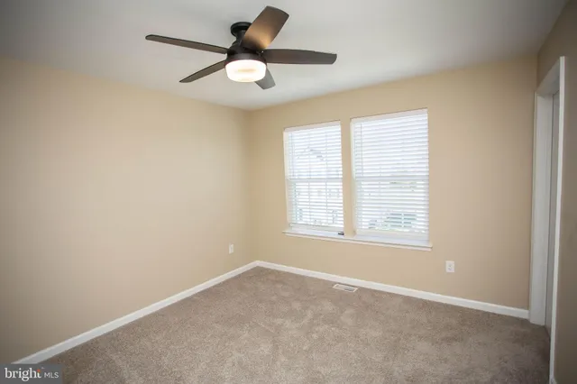 an empty room with a ceiling fan and a window