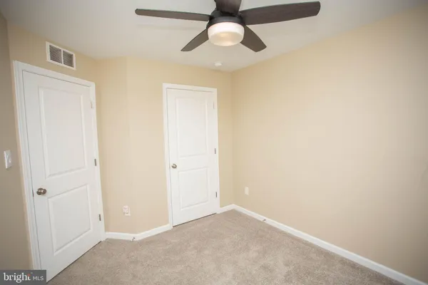 an empty room with chandelier fan and windows