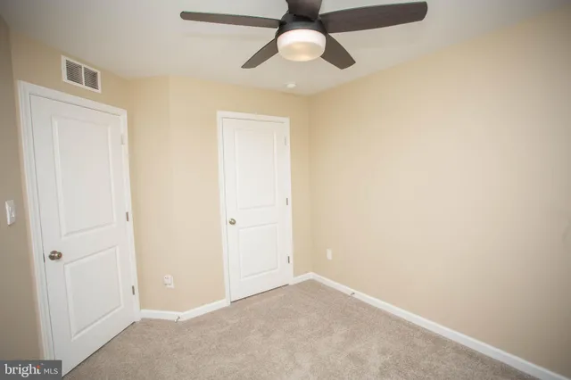 an empty room with chandelier fan and windows