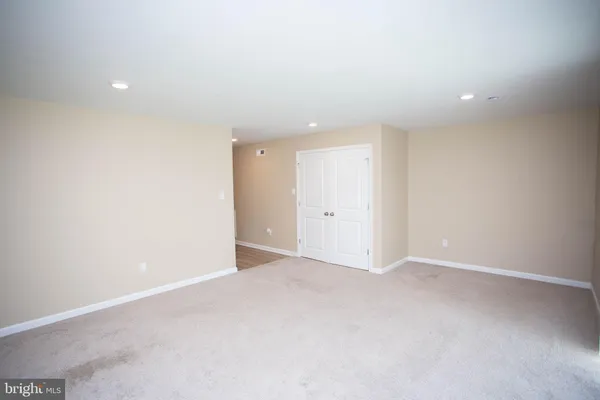 a view of an empty room and wooden floor and a ceiling fan