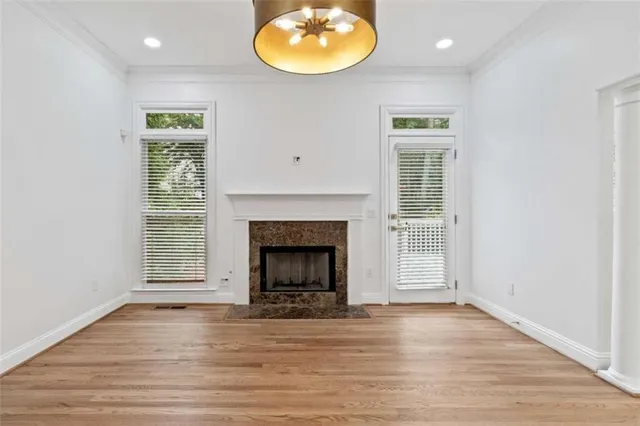 an empty room with wooden floor fireplace and window