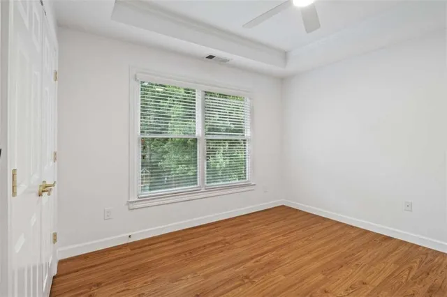 a view of an empty room with wooden floor and a window