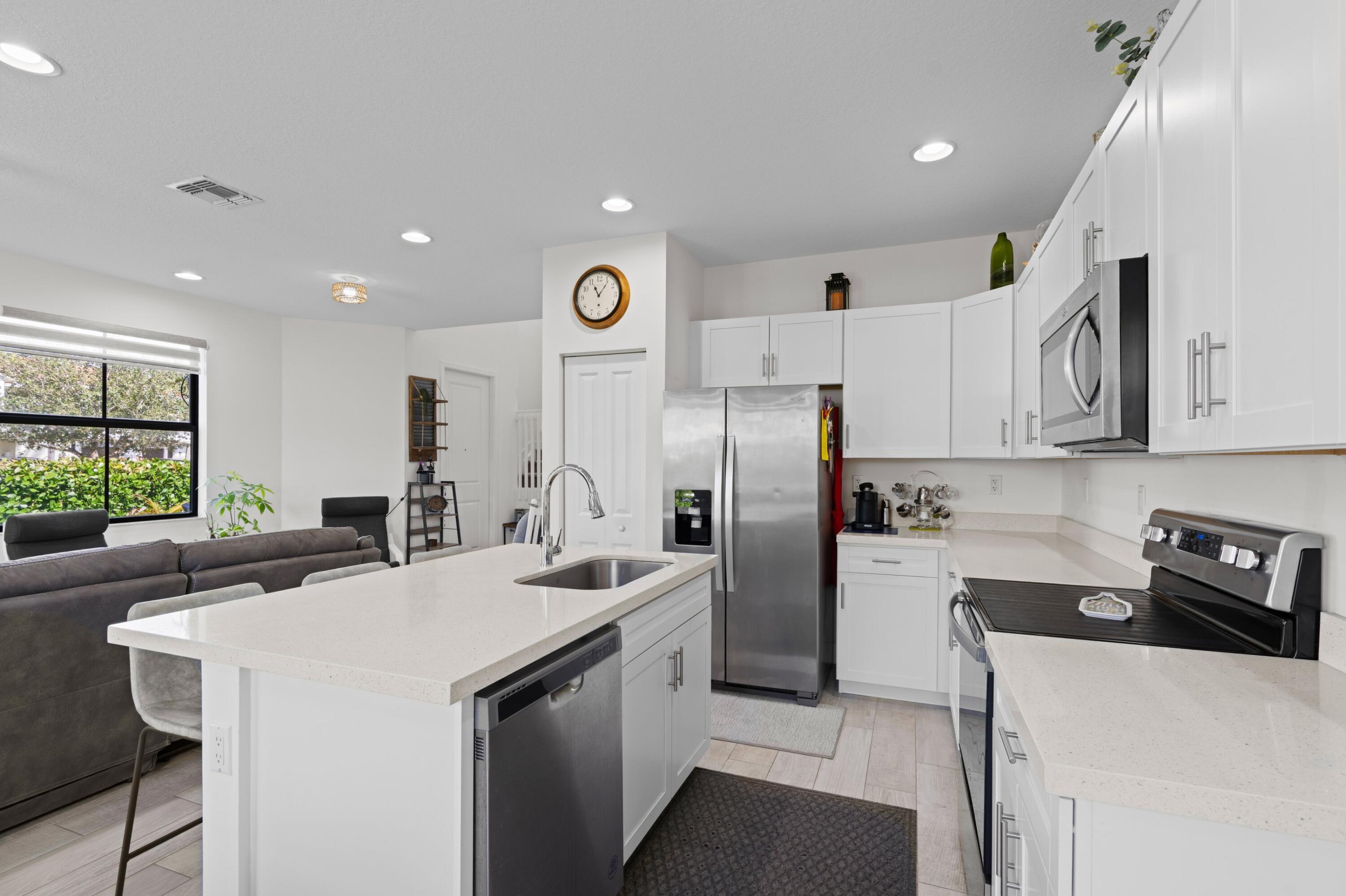 4021 Sycamore Cove Riviera Beach, FL 33410 - Photo 11 of 37 a kitchen with a sink a refrigerator and cabinets