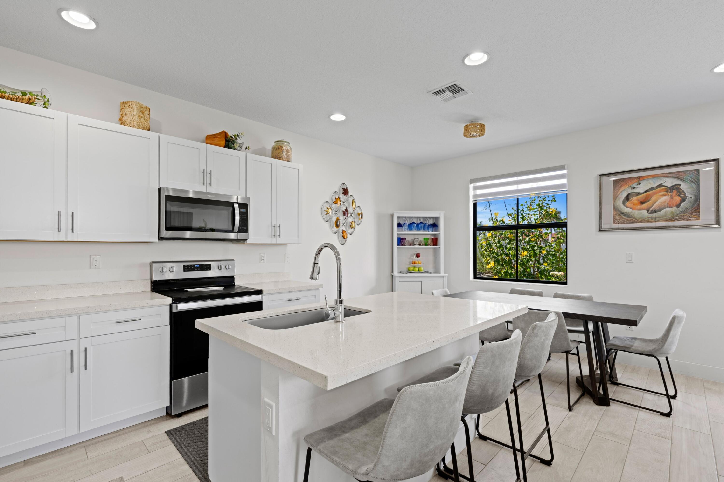 4021 Sycamore Cove Riviera Beach, FL 33410 - Photo 12 of 37 a kitchen with stainless steel appliances a white table chairs and a refrigerator