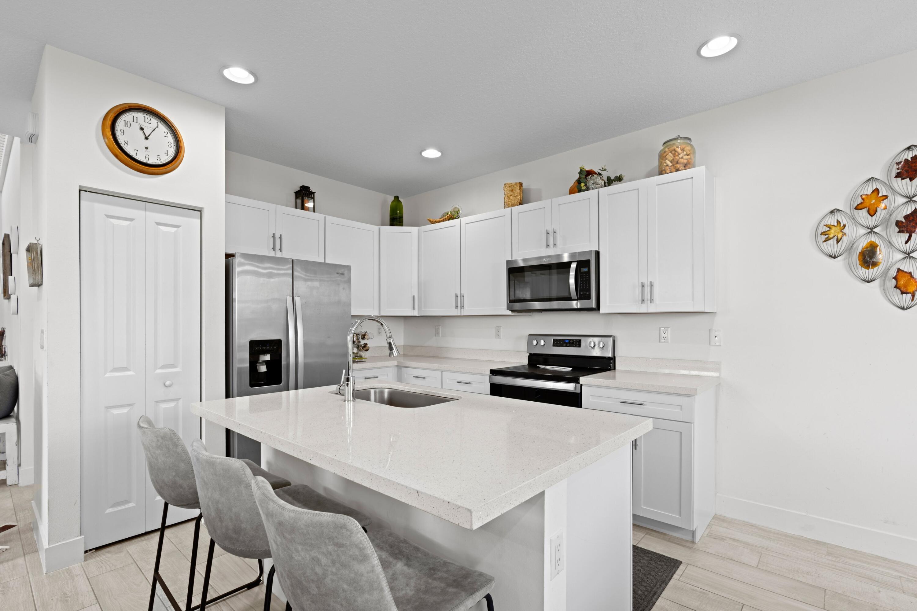 4021 Sycamore Cove Riviera Beach, FL 33410 - Photo 16 of 37 a kitchen with stainless steel appliances a refrigerator a stove a sink and a refrigerator with wooden floor