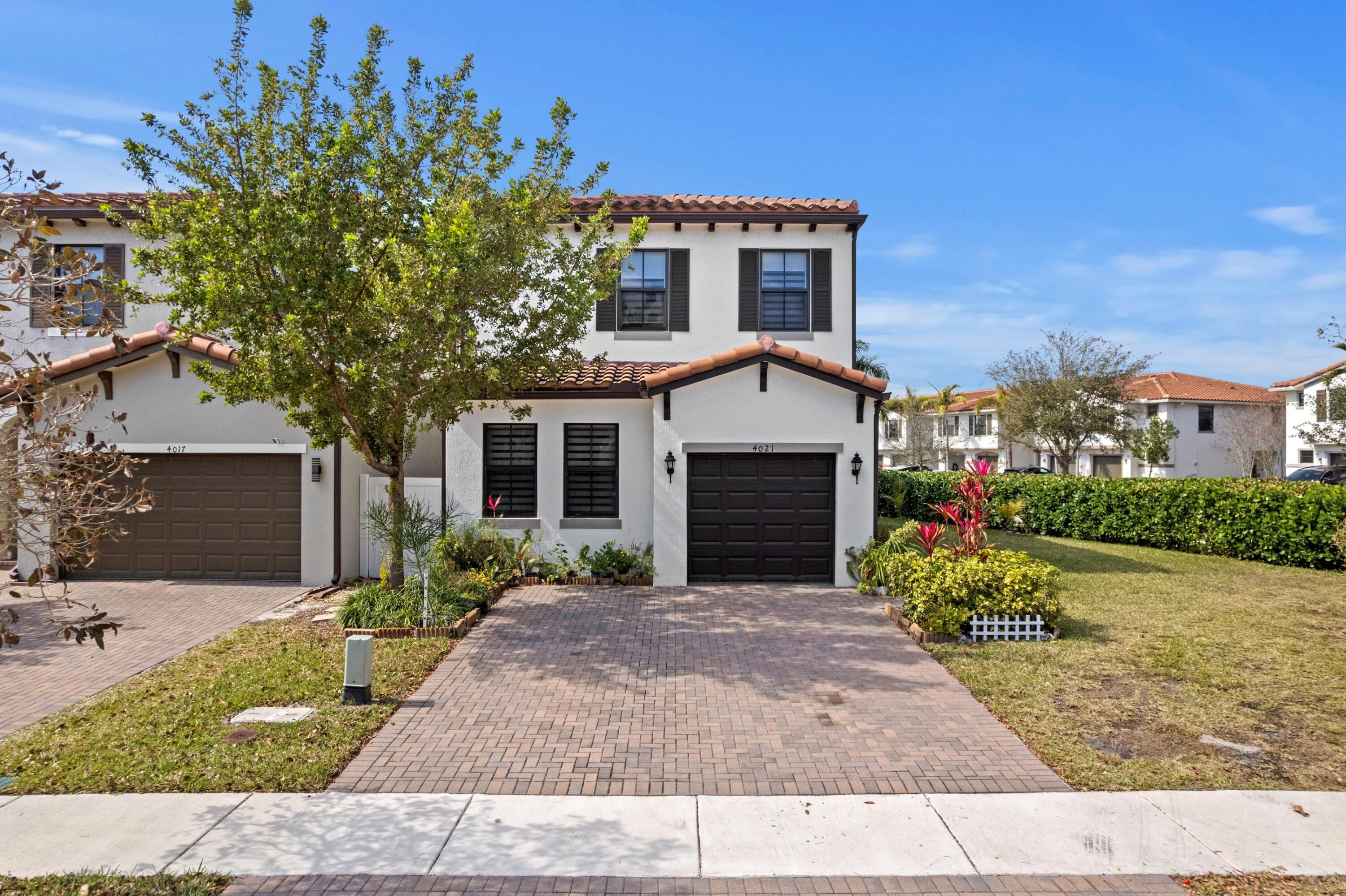 4021 Sycamore Cove Riviera Beach, FL 33410 - Photo 2 of 37 a front view of a house with a garden