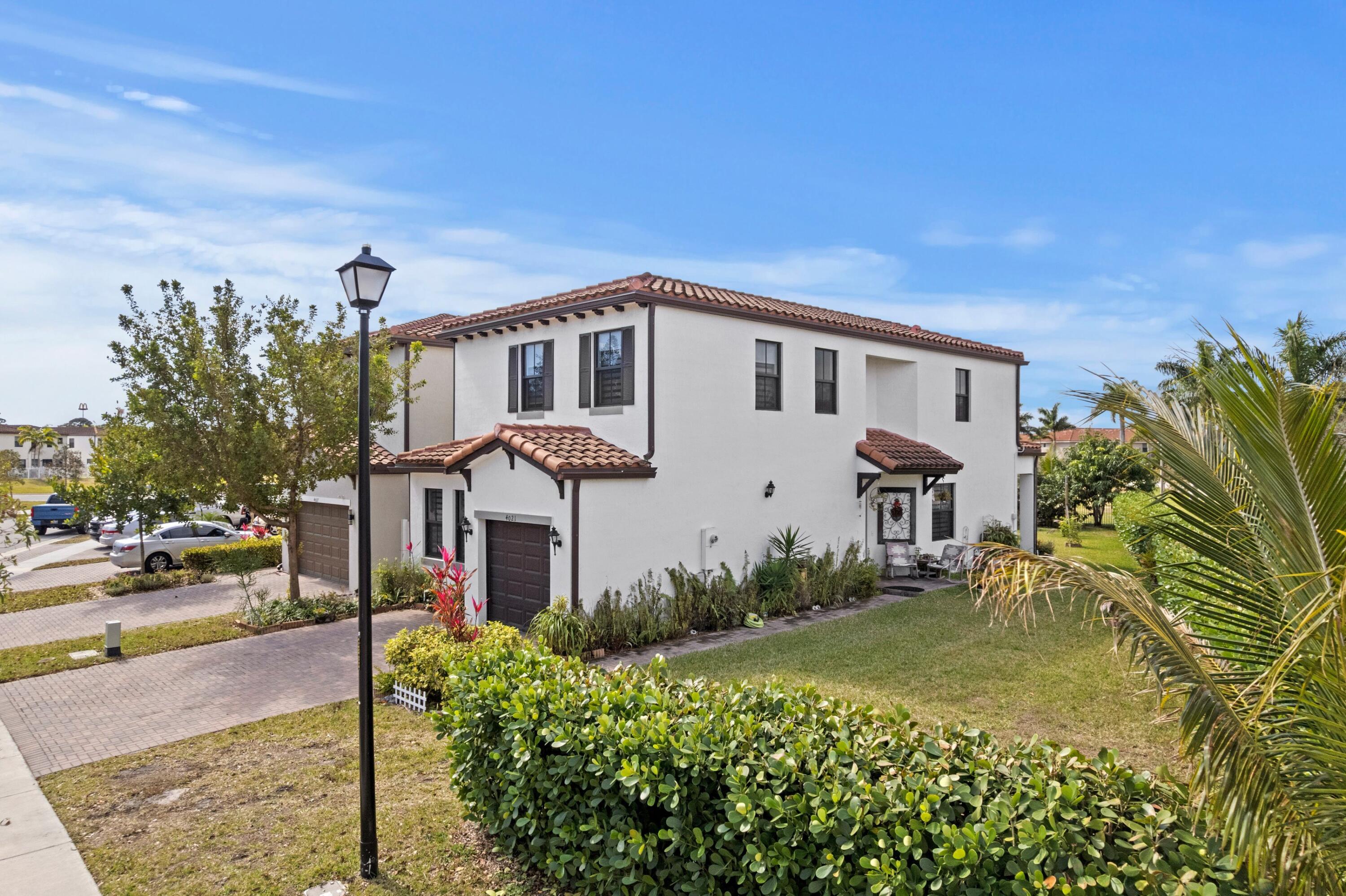 4021 Sycamore Cove Riviera Beach, FL 33410 - Photo 3 of 37 a front view of a house with garden