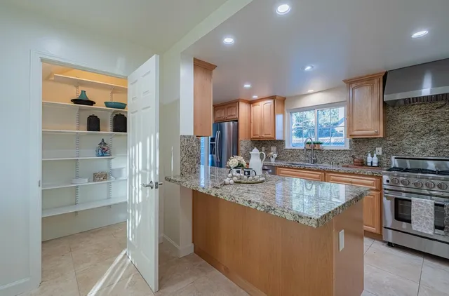 a kitchen with kitchen island granite countertop a large counter top stainless steel appliances and cabinets