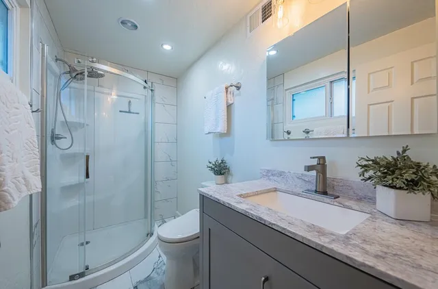 a bathroom with a granite countertop sink a toilet and shower