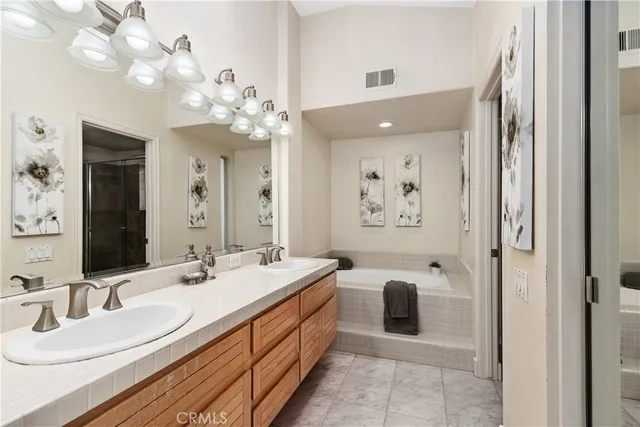 a spacious en suite bathroom with a double vanity sink bathtub and a mirror
