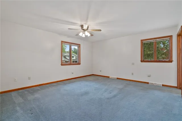 an empty room with windows and ceiling fan