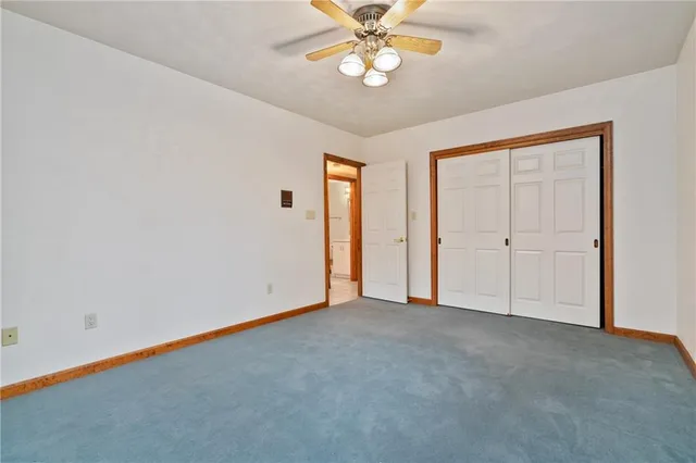 an empty room with a chandelier fan and windows
