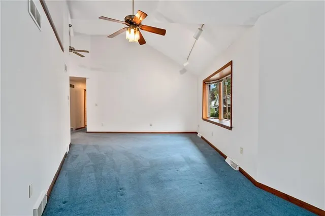 an empty room with windows and ceiling fan