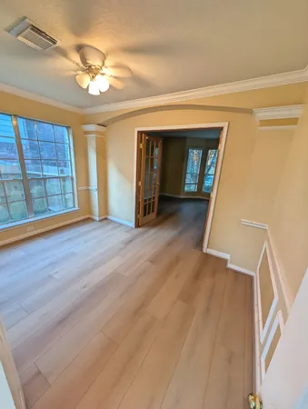 a view of an empty room with wooden floor and a window
