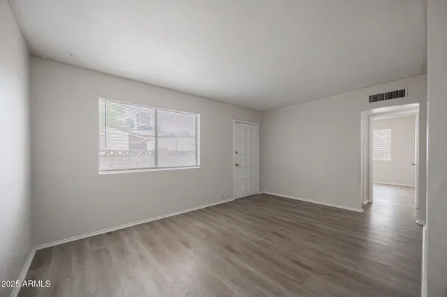an empty room with wooden floor and windows