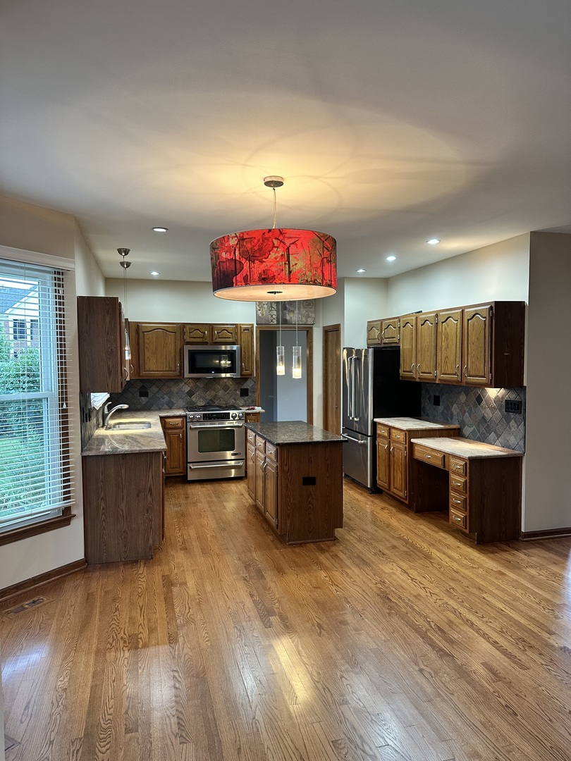 1592 Wakefield Court Mundelein, IL 60060 - Photo 7 of 25 a kitchen with stainless steel appliances kitchen island wooden cabinets and granite counter tops