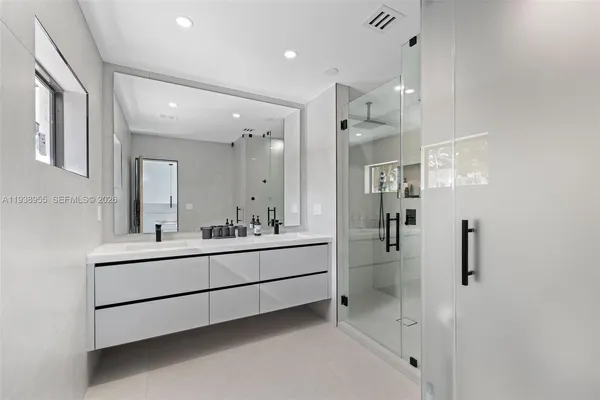a bathroom with a double vanity sink mirror and shower